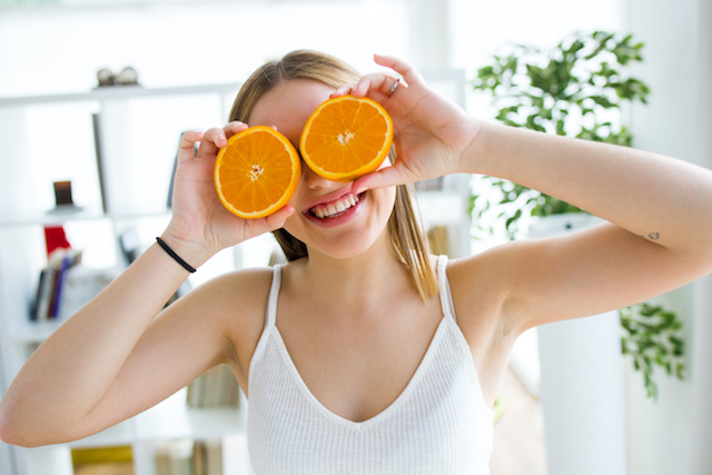 beautiful young woman playing with orange fruits.