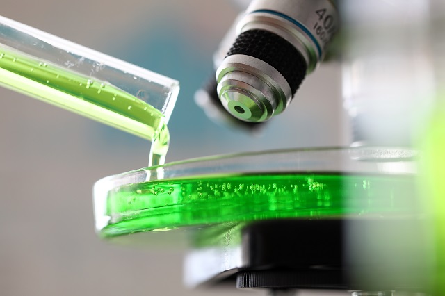 microscope with green substance pouring out from test tube