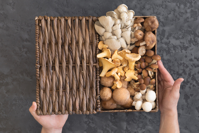 view from above of wicker basket with forest rare delicious edible mushrooms on a dark textural background, flat lay.